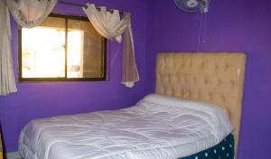 a bed in a purple bedroom with a window at Kalebalika Meanwood KKIA Apartments in Chongwe