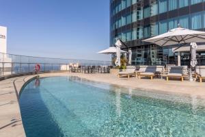 a swimming pool with chairs and umbrellas on a building at Oceans Apartments Balcony Suites in the Radisson Blu Hotel Building Tower,Durban,Umhlanga in Durban