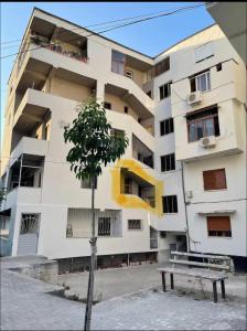 a white building with a tree in front of it at Apartament pushim pogradec in Pogradec