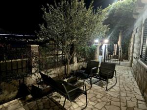 two chairs and a tree on a patio at night at KiM in Mokošica