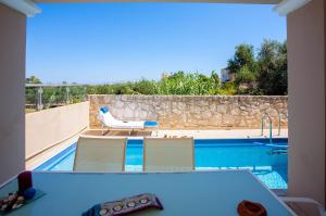 a view of a swimming pool with a table and chairs at Pyrgos Spring pool apartment in Maleme
