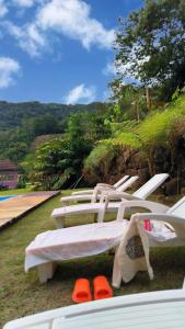a group of white lounge chairs sitting on the grass at Villa Toca da Toca Lumiar in Nova Friburgo