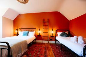 two beds in a room with red walls at Talfryn Cottages in Betws-y-coed