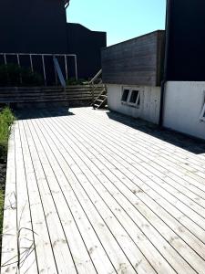 a wooden deck in front of a building at Cozy Holiday Home in Sandavágur +24 photos