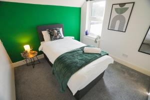 a green room with a bed and a green wall at The Tenstay -Luxury 5BR Home Close To All in Ifield