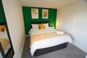 Un dormitorio con una cama con una pared verde. en The Tenstay -Contractor-Friendly 5BR Home Close To All, en Ifield