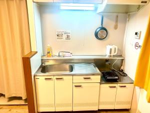 a small kitchen with a sink and a stove at ゲストハウスEn 割子川 in Kitakyushu