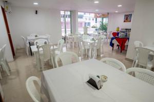 a dining room with white tables and white chairs at Hotel ITACO in Cartagena de Indias