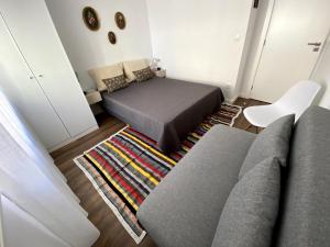 ein Zimmer mit einem Sofa, einem Bett und einem Teppich in der Unterkunft Casa da Covilhã - Pedra e Lã in Covilhã