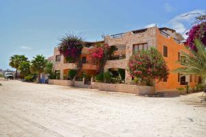 um edifício com flores ao lado de uma estrada de terra em BookingBoavista - Apartments em Sal Rei