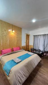 a bedroom with a large bed with pink pillows at Hotel Kaza Manjushree in Kaza