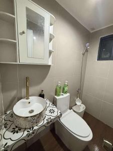 a white bathroom with a sink and a toilet at 2 bedroom cute log house in Bacolod- near NGC in Bacolod