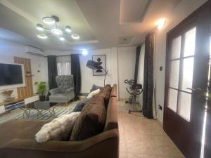 un salon avec un canapé et une télévision dans l'établissement Luxury apt,Secure estate,Parking,10mins to Airport, à Hausa 5 autres photos