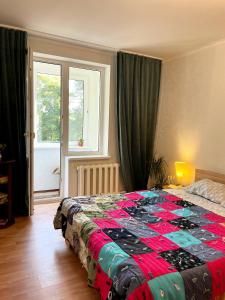 Un dormitorio con una cama con una colcha colorida encima. en Lake Park Apartment, en Chişinău