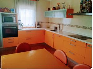 a kitchen with orange cabinets and a table with chairs at Acogedora casa con jardín in Castellanos de Villiquera