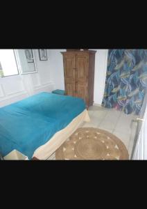 a bedroom with a bed with blue sheets and a table at Villa Kowosol in Le Marin +10 photos