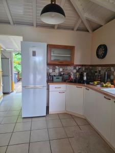 a kitchen with white cabinets and a white refrigerator at Villa Kowosol in Le Marin