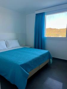 a blue bedroom with a bed and a window at Villa Andrea in Cala Sinzias