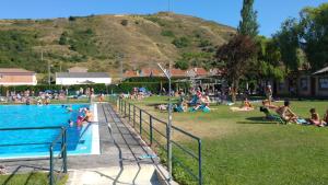 un grupo de personas yaciendo en la hierba junto a una piscina en Albergue MUNICIPAL El Corro de Belorado, en Belorado