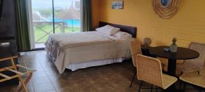 a bedroom with a bed and a table and a window at Sotavento Apart Hotel in La Paloma