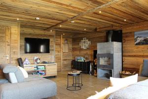 a living room with a couch and a tv at Chambres et Tables d'Hôtes Le Choton à Nono - Col du Joly Beaufortain in Hauteluce