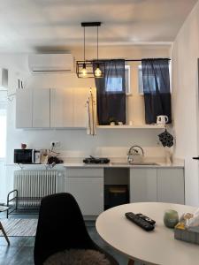 a kitchen with white cabinets and a table and a sink at Elephant Apartman in Komárno