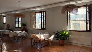 a restaurant with white tables and chairs and windows at Hotel los Tilos in Beteta