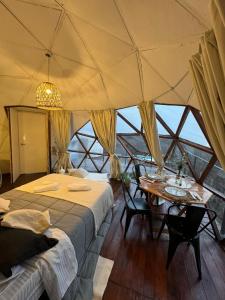 a bedroom with two beds and a table in a tent at Glamping il Tramonto in Villa Amancay