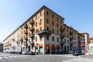 un grand bâtiment dans une rue de la ville avec des voitures garées dans l'établissement Appartamento Martini Stazione Centrale, à Milan
