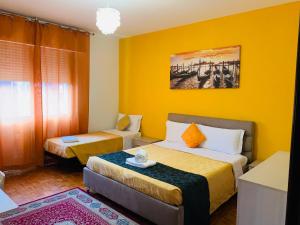 a hotel room with two beds and a yellow wall at Venice Day Apartment in Mestre