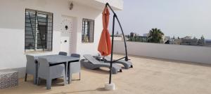 a balcony with a table and chairs and an umbrella at Rooftop Apartment in Monastir
