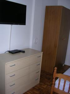 a bedroom with a dresser with a television on the wall at Apartment Perkovic Jadranka in Kornić