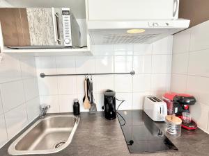 a small kitchen with a sink and a microwave at Studio des brises centre-ville in Lorient +8 photos