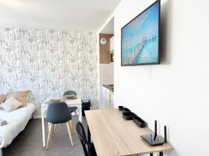 a living room with a table and a tv on a wall at Studio des brises centre-ville in Lorient