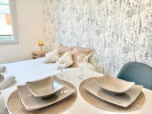 a table with plates and glasses on a bed at Studio des brises centre-ville in Lorient