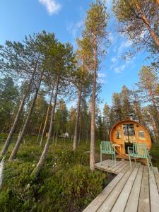 a tiny house in the woods with a wooden deck at LaplandLiv Glampingtent with private sauna at the lake! in Mellanström