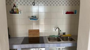 a kitchen with a sink and a tiled wall at Eolian Villa Mare - Floating over the sea in San Salvatore +35 photos
