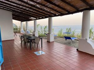 a patio with a table and chairs and the ocean at Eolian Villa Mare - Floating over the sea in San Salvatore