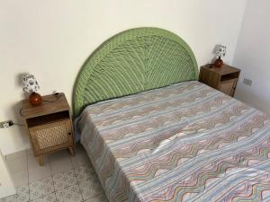 a bed with a green headboard in a bedroom at Eolian Villa Mare - Floating over the sea in San Salvatore