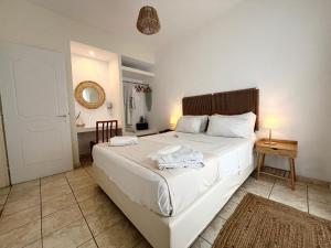 斯卡拉Koukounari Apartments的卧室里有一张白色的大床和一张桌子