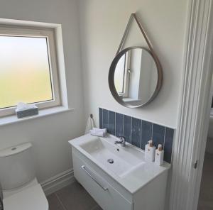 a white bathroom with a sink and a mirror at Eastbury House near Garryvoe Hotel & Ballymaloe House in Cork