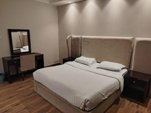 ein Schlafzimmer mit einem großen Bett mit einem Spiegel und einem Tisch in der Unterkunft خزامى للشقق المخدومة in Sufan