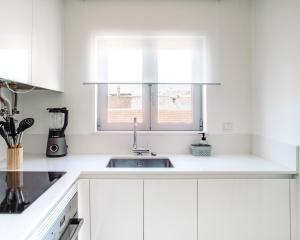 a white kitchen with a sink and a window at Salicórnia in Olhão