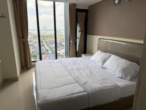 a bed in a hotel room with a large window at Pollux Habibie Deluxe Sea View By Superstay in Batam Center
