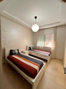 a bedroom with two beds and a chandelier at Suite Horizon in Mohammedia
