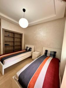a bedroom with two beds and a chandelier at Suite Horizon in Mohammedia +3 photos