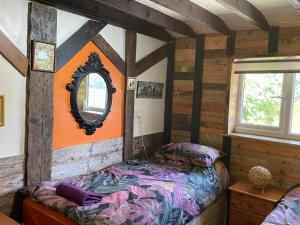 a bedroom with a bed and a mirror on the wall at Yarm Cottages The Byre Sleeping 4 Next to Fox Covert Pub in Kirk Leavington