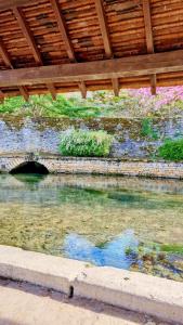 a body of water under a wooden roof at Caravane Zen & Jacuzzi proche des grottes de Bèze in Bèze