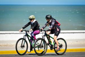 two people riding bikes on a road near the ocean at Hostal del Mar - Tolu in Tolú