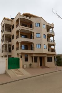 a tall building with a green garage in front of it at Bekouvi Smart Suite - City & Sea in Cotonou